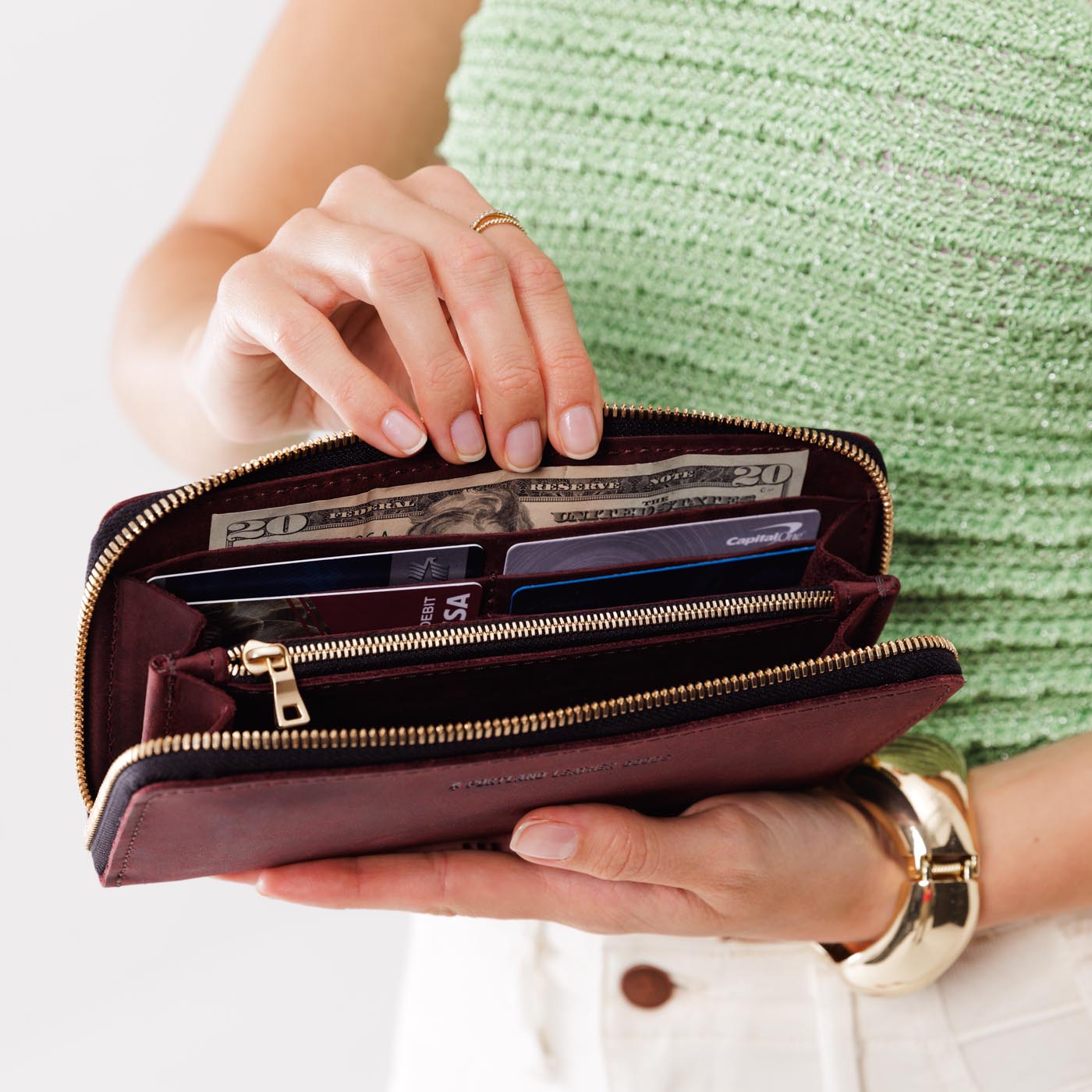 Merlot | Model holding large accordion leather wallet with zipper open