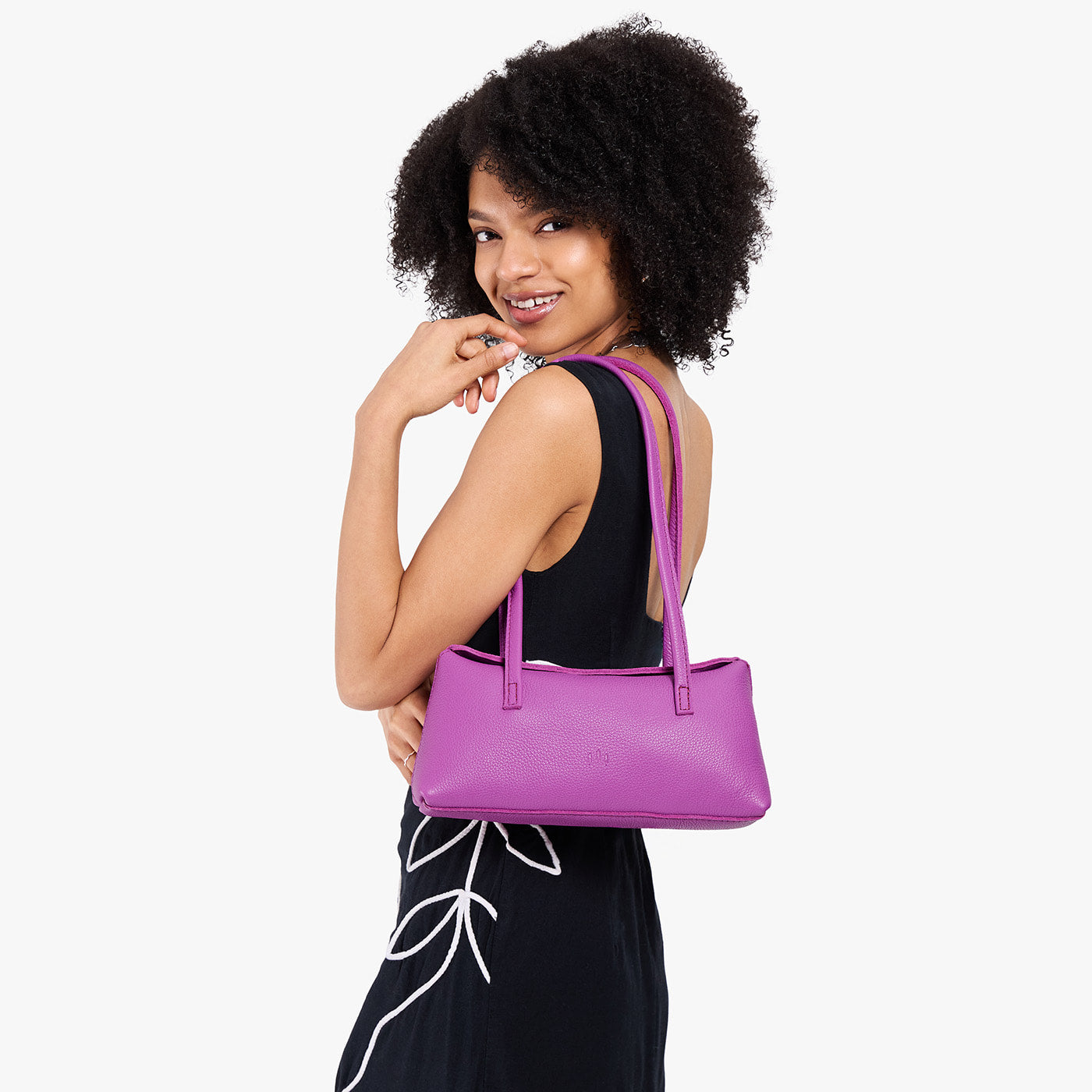 Cattleya | Model wearing black dress carrying leather bowler bag with magnetic closure