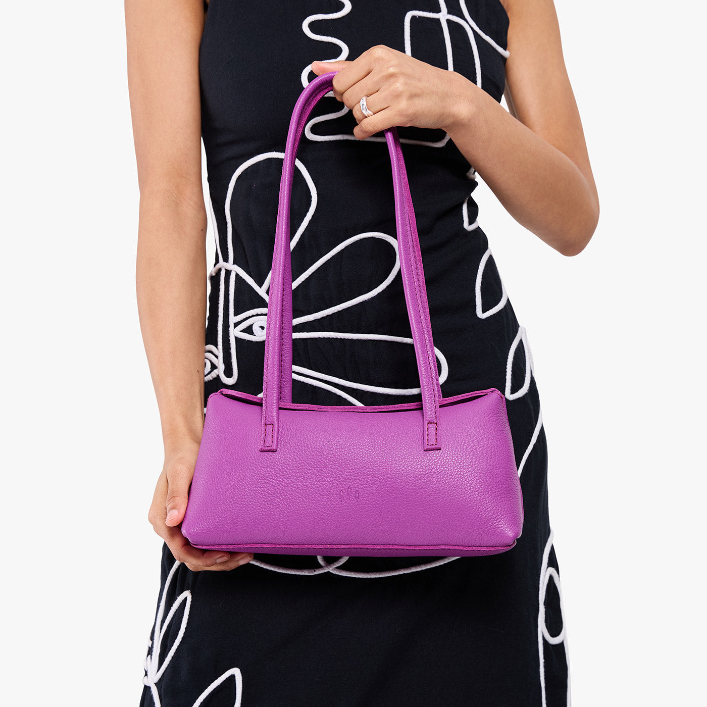 Cattleya | Model wearing black dress holding leather bowler bag with magnetic closure