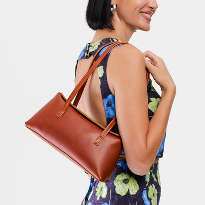 Chestnut | Woman wearing a warm brown leather bowler bag against a white background