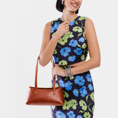 Chestnut | Woman wearing a warm brown leather bowler bag against a white background