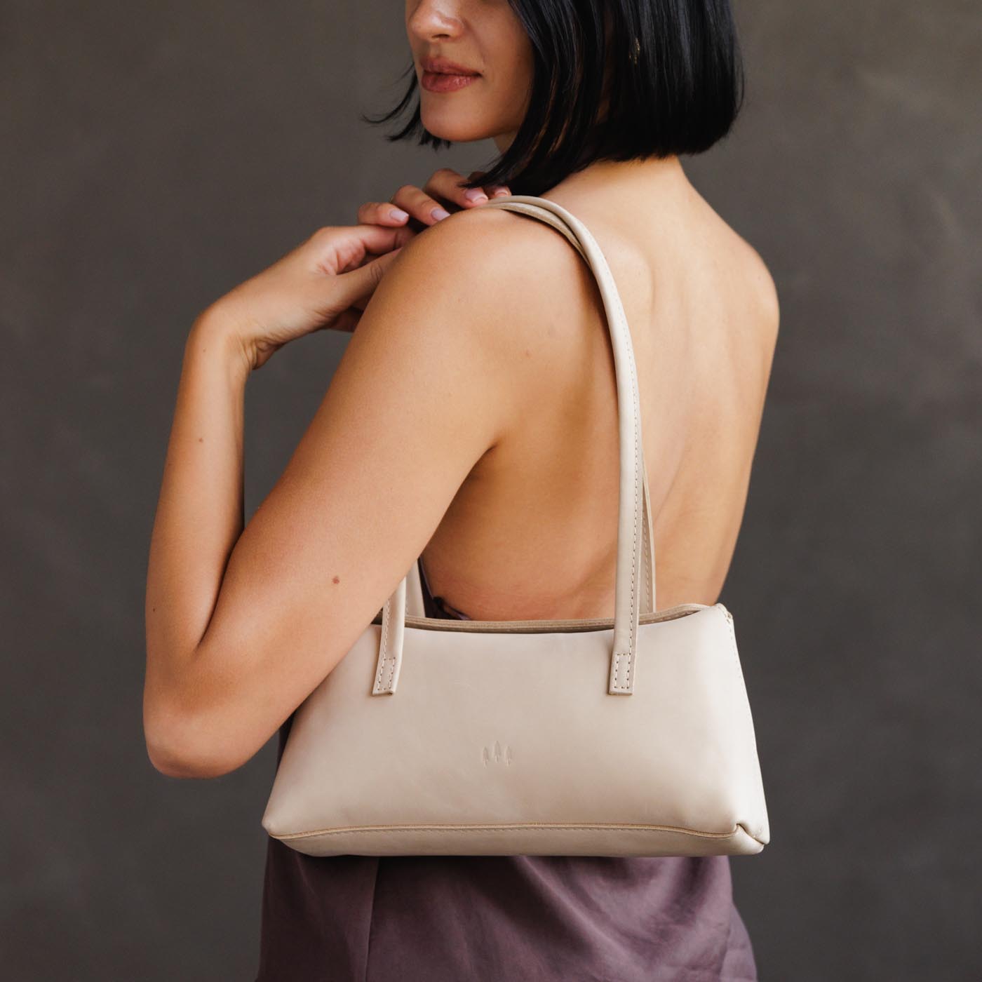 Dragon Bone | Woman wearing a white leather bowler bag against a white background