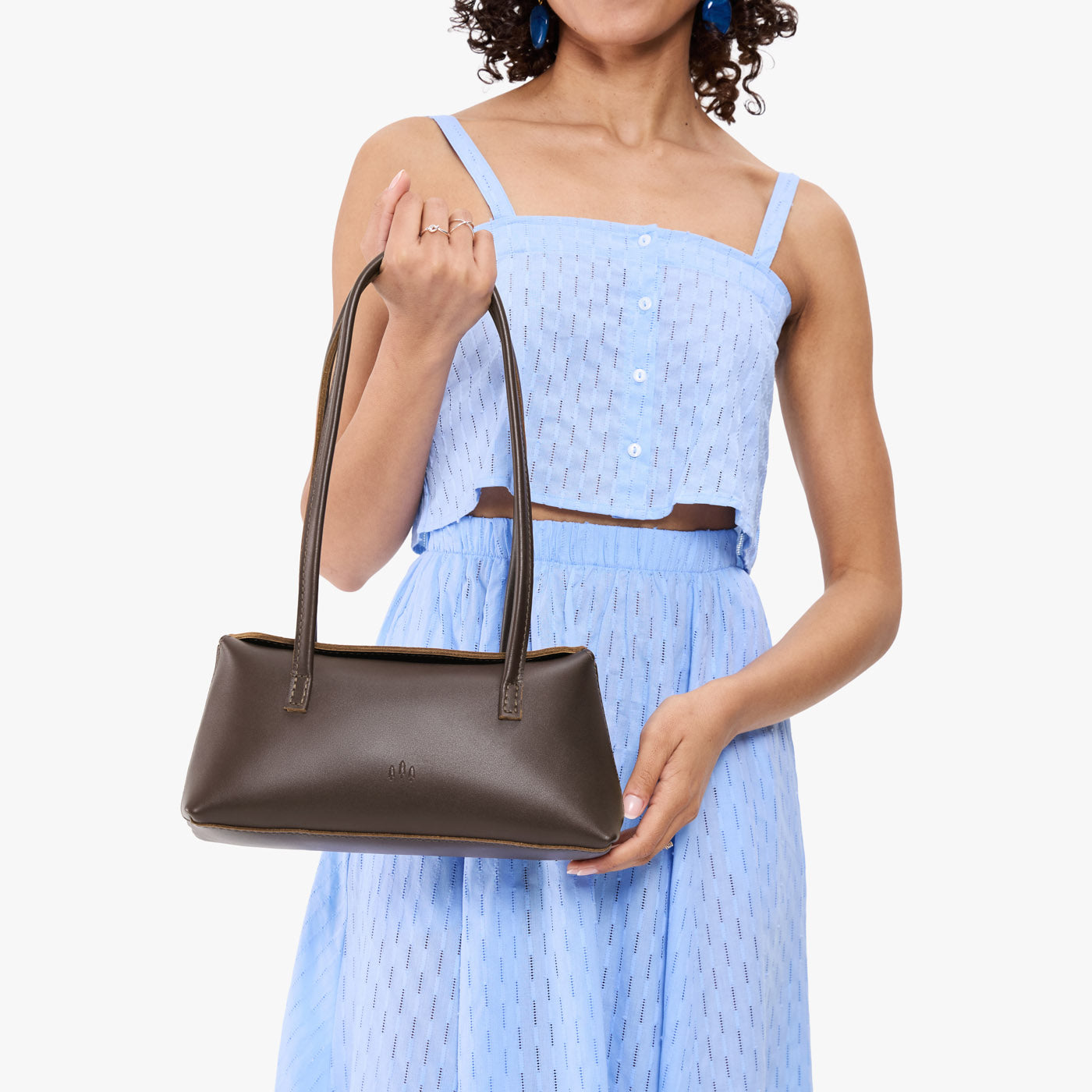 Grizzly | Model wearing light blue skirt with matching top holding leather bowler bag with magnetic closure