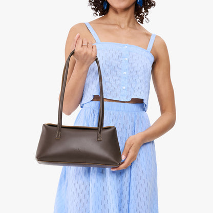 Grizzly | Model wearing light blue skirt with matching top holding leather bowler bag with magnetic closure
