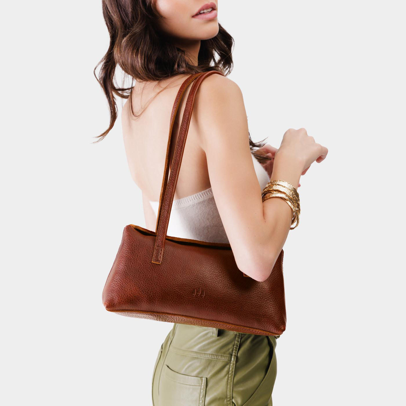 Nutmeg | Woman wearing a light brown leather bowler bag against a white background
