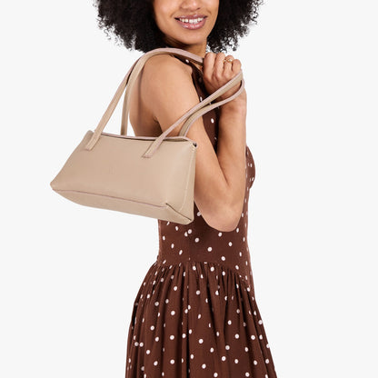 Oatmilk | Model wearing brown dress with white polka dots carrying leather bowler bag with magnetic closure