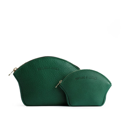 Bacalar | Comparison shot of small and large seashell shaped leather makeup bags with curved top zipper and flat bottom