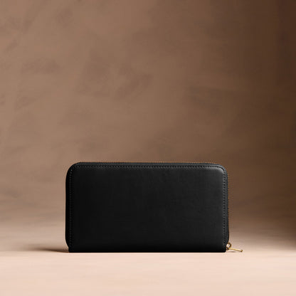 Onyx | Full zip around wallet with a strap on a brown background