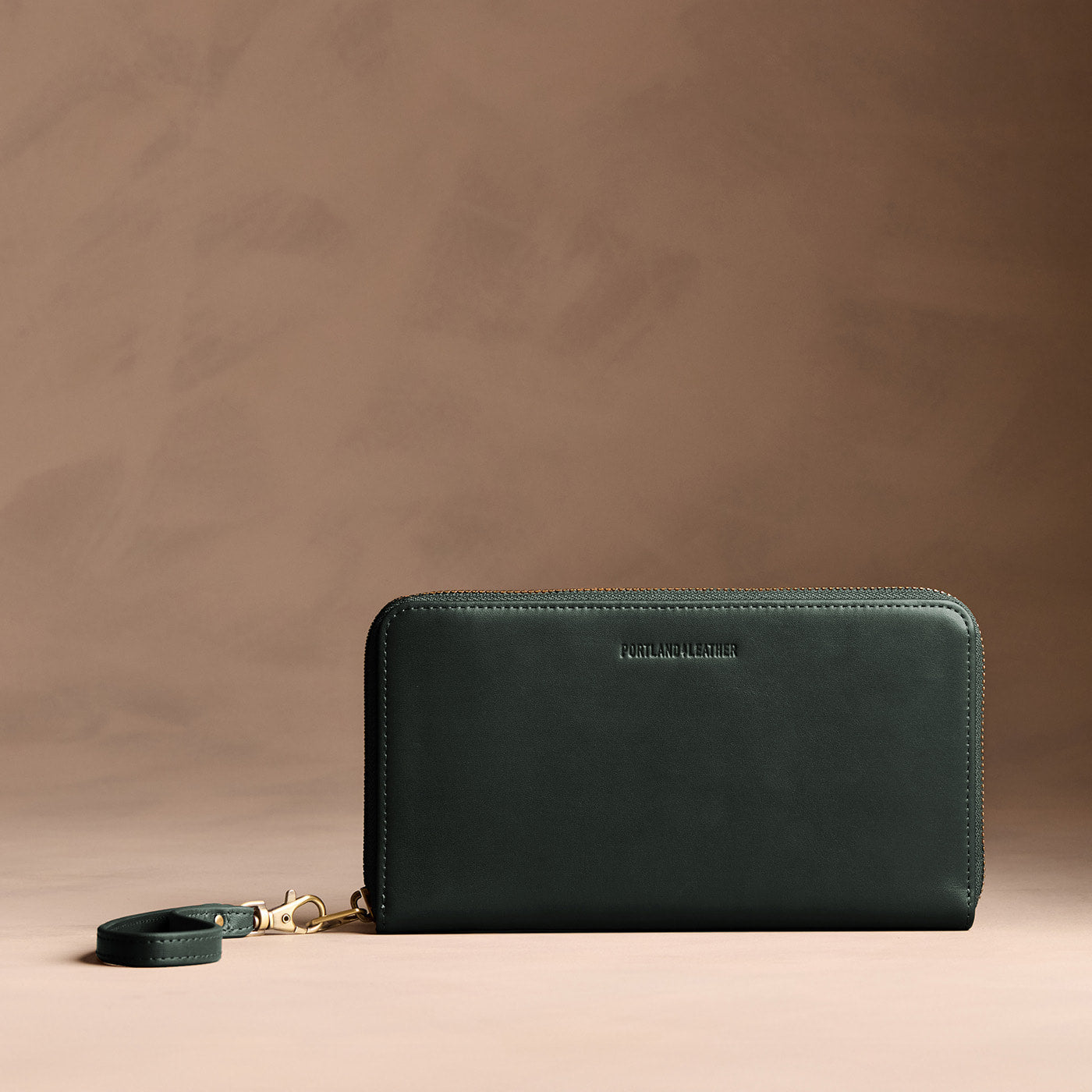 Regent Green | Full zip around wallet with a strap on a brown background