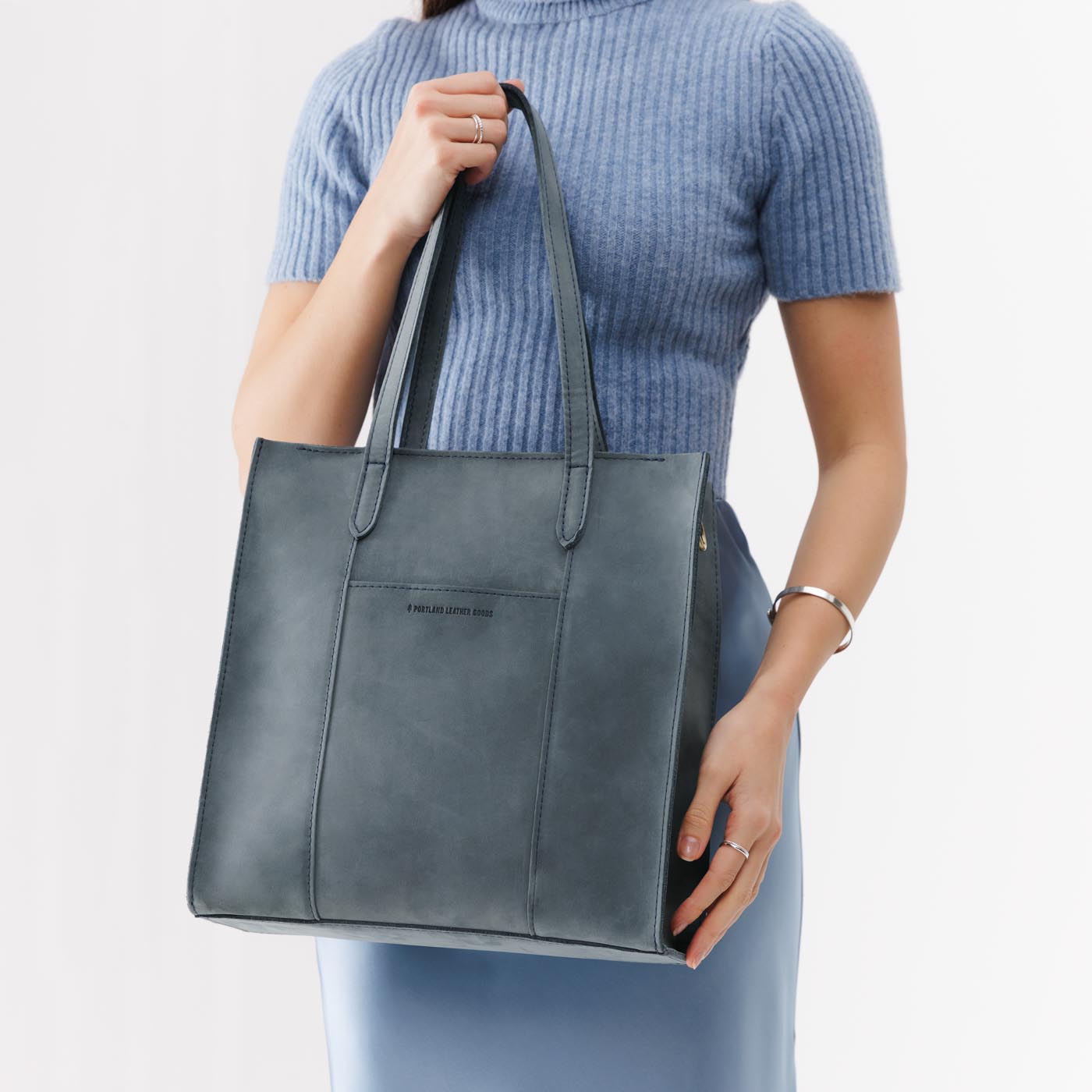Storm*North/South | Model holding structured large tote bag with overlapping panels and crossbody strap
