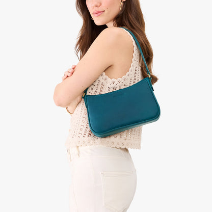 Westward Blue*Small | Model carrying petite bean shaped shoulder bag with a zipper closure