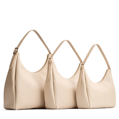 Pebbled Bone | Size comparison image of oversized, large, and medium u-shaped, flat-bottomed leather shoulder bags with adjustable strap