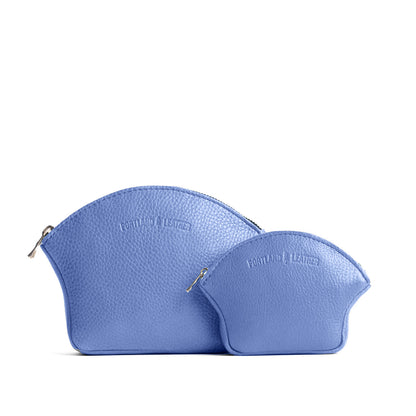 Aster | Comparison shot of small and large seashell shaped leather makeup bags with curved top zipper and flat bottom