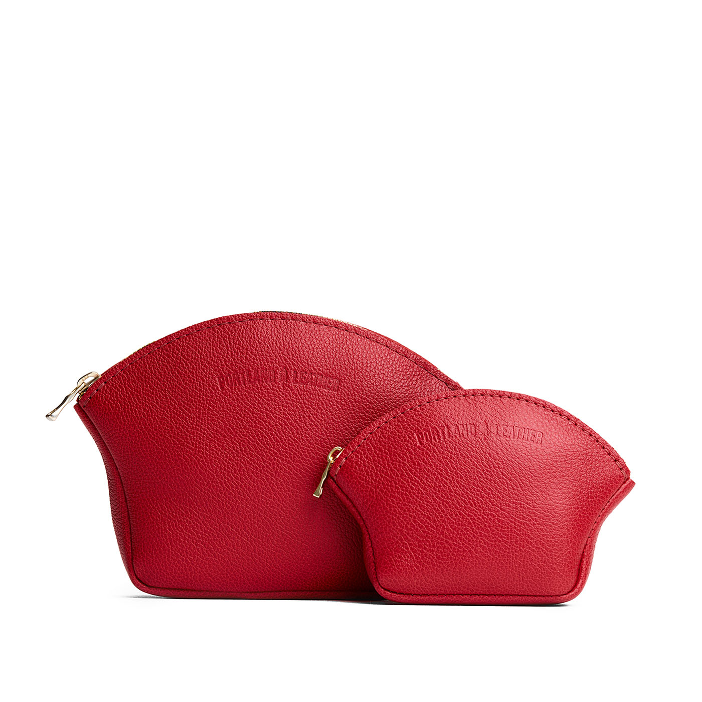 Cherry | Comparison shot of small and large seashell shaped leather makeup bags with curved top zipper and flat bottom