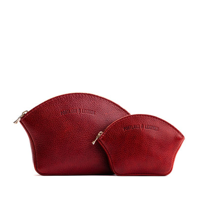 Chili Red | Comparison shot of small and large seashell shaped leather makeup bags with curved top zipper and flat bottom