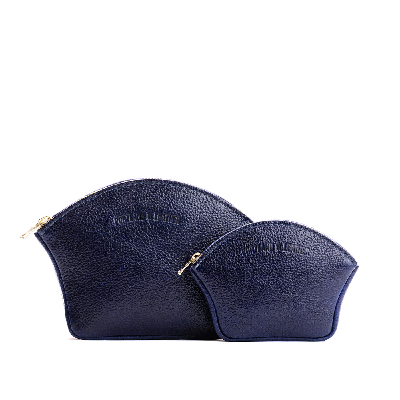 Cobalt | Comparison shot of small and large seashell shaped leather makeup bags with curved top zipper and flat bottom