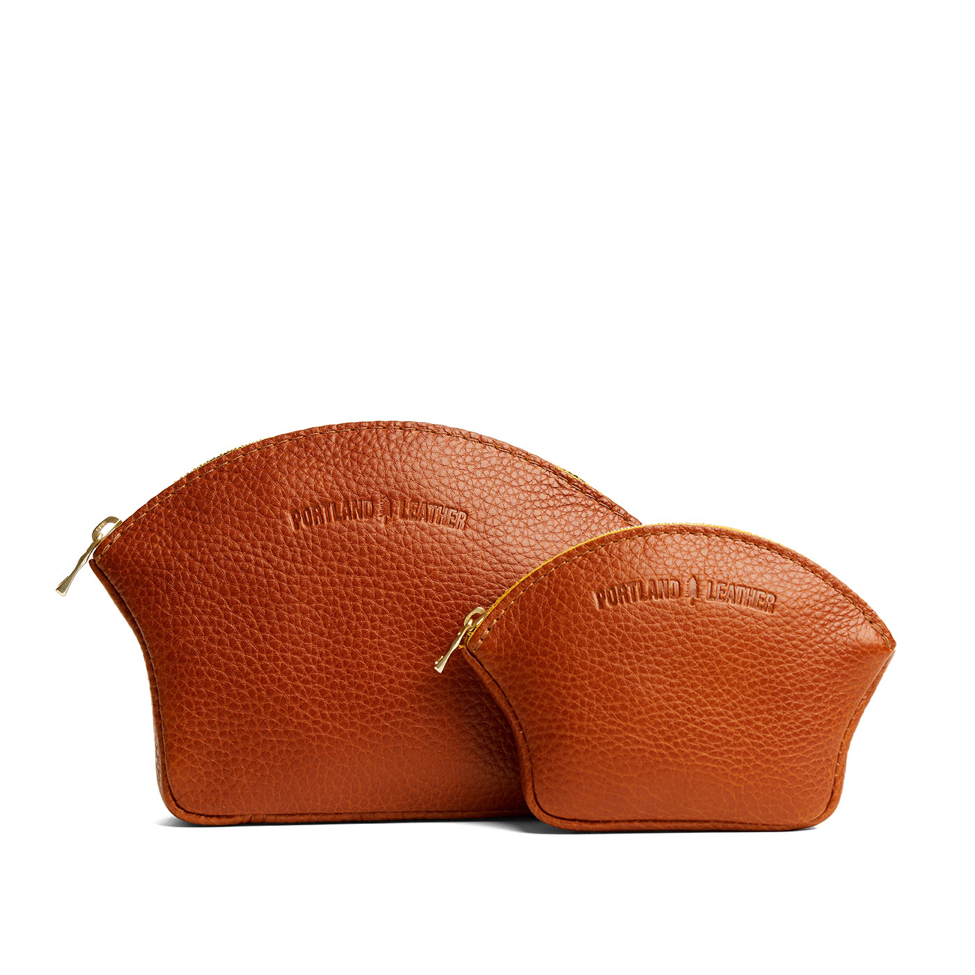 Sienna | Comparison shot of small and large seashell shaped leather makeup bags with curved top zipper and flat bottom