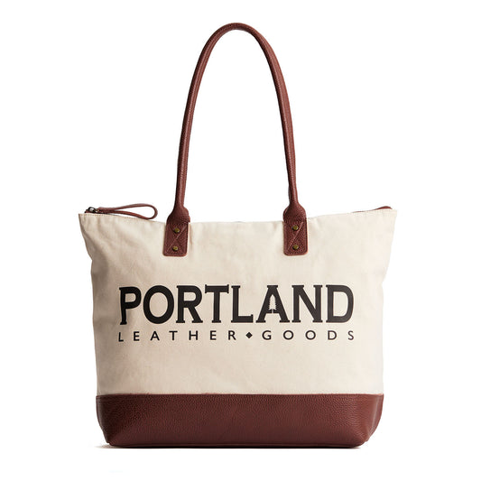 Canvas tote with zipper, leather bottom, and leather handles on a white background
