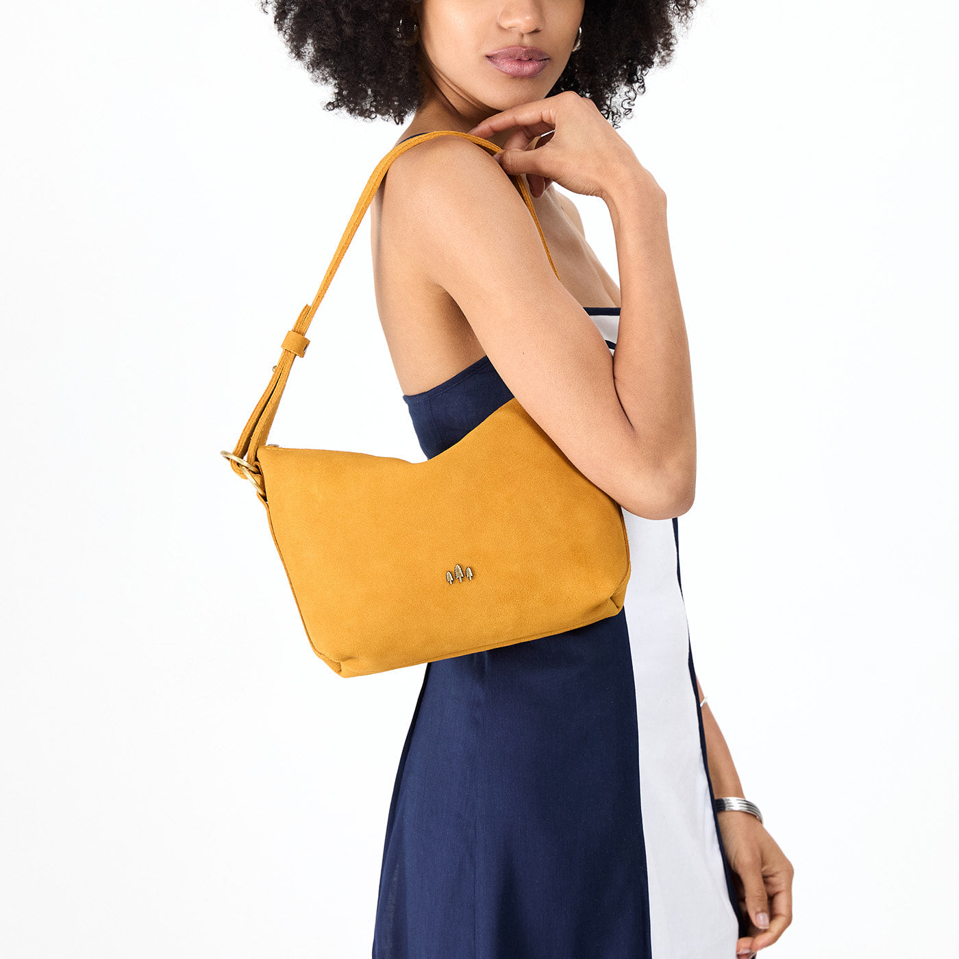 Dijon*Small | Model holding a Slouchy Shoulder Bag that has a zipper opening and three metal tree emblems