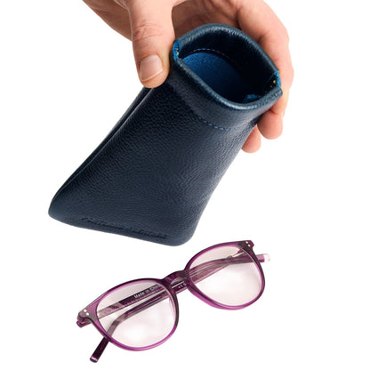 Boreal | Model hand holding open leather glasses case with hidden metal spring closure above a pair of glasses