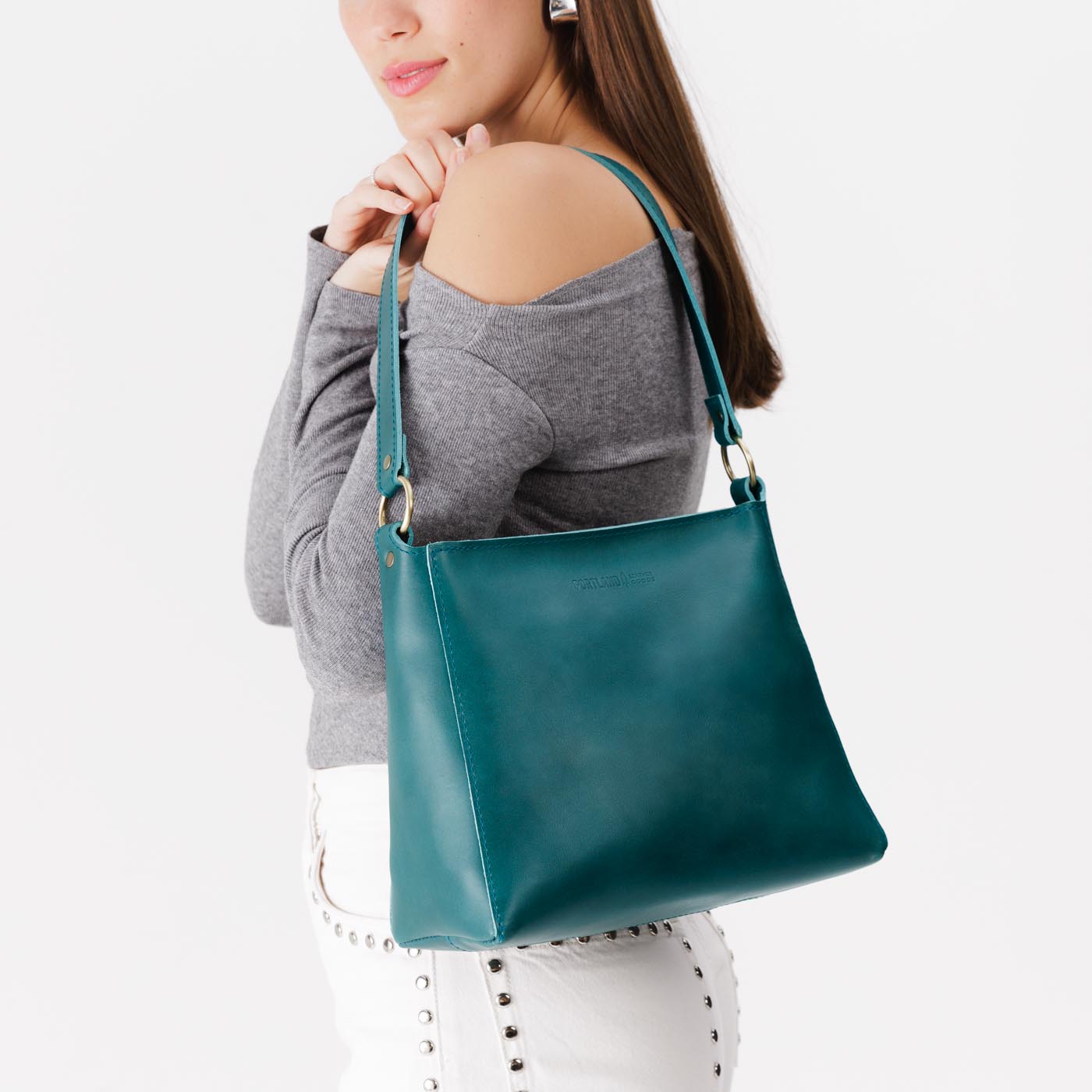 Caribbean*Small | Model carrying leather triangular shoulder bag with zipper top closure and wide shoulder strap