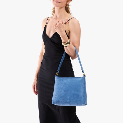 Cornflower | Model holding a triangular shoulder bag with antiqued brass finished