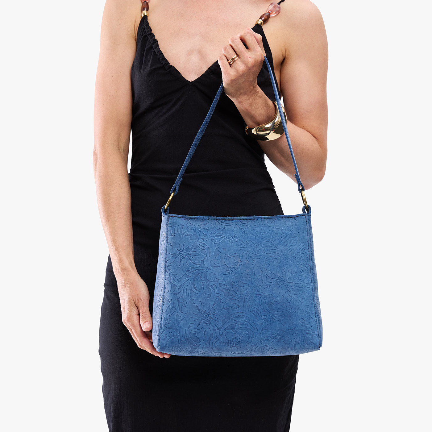 Cornflower | Model holding a triangular shoulder bag with antiqued brass finished