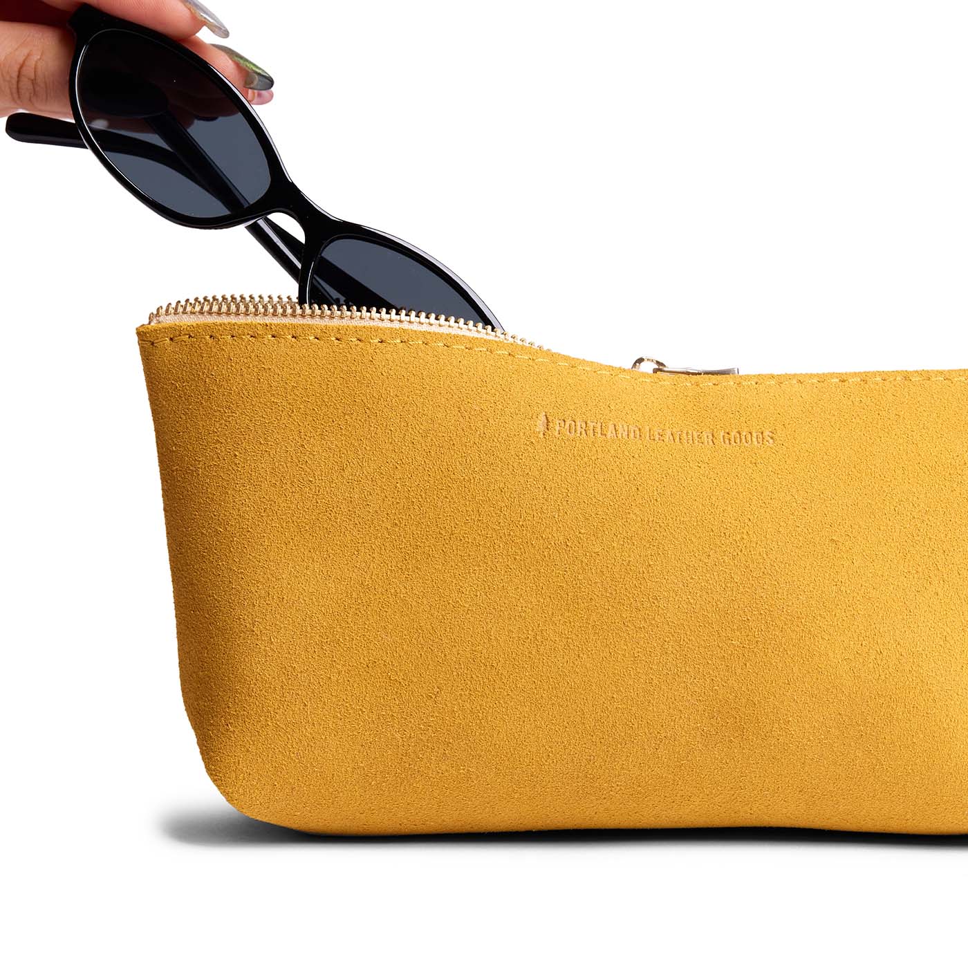 Dijon | Model hand pulling pair of sunglasses from leather utility bag pouch with top zipper