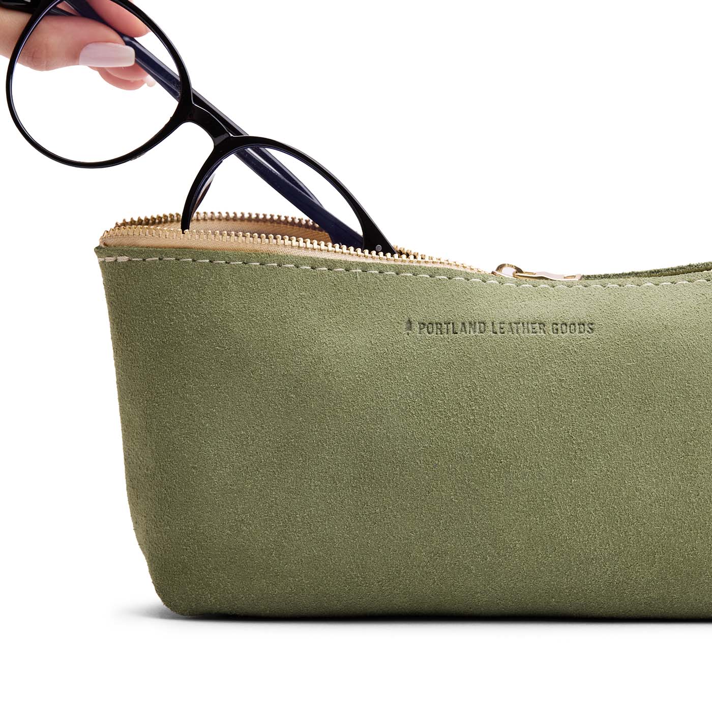 Laurel | Model hand pulling pair of glasses from leather utility bag pouch with top zipper