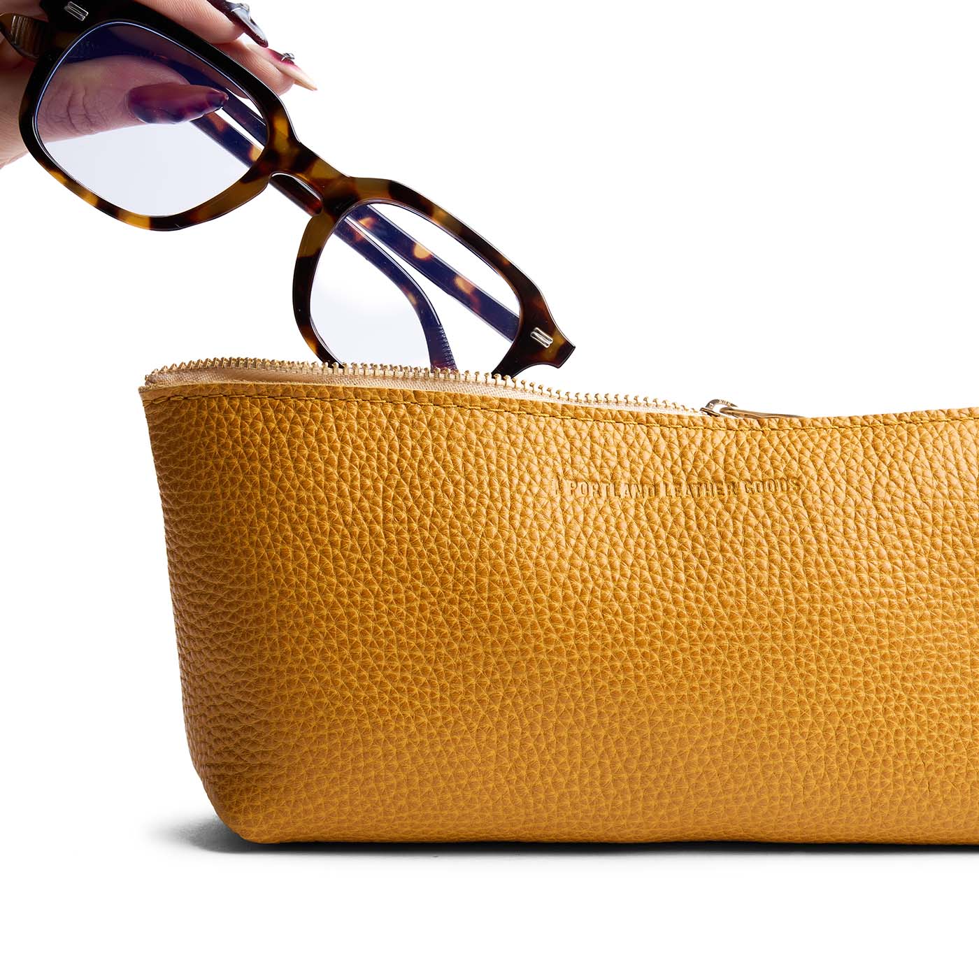 Sunshine | Model hand pulling pair of glasses from leather utility bag pouch with top zipper