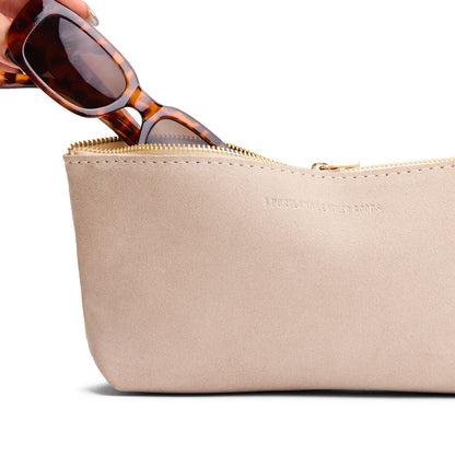 Taupe | Model hand pulling pair of sunglasses from leather utility bag pouch with top zipper