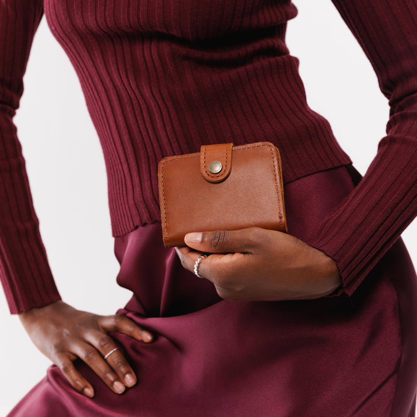 Honey | Model holding small leather bifold wallet with snap closed