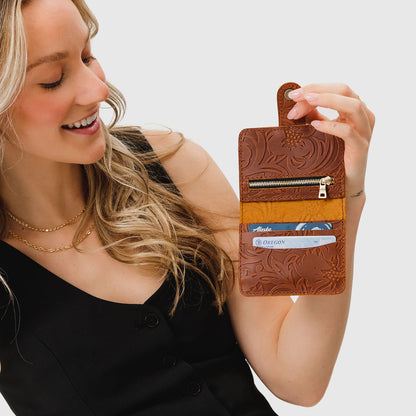 Meadow | Model holding small leather bifold wallet with snap open
